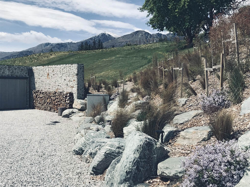 Schist glacial boulders, native grasses and shrubs forming a naturalistic garden at Shotover River House.