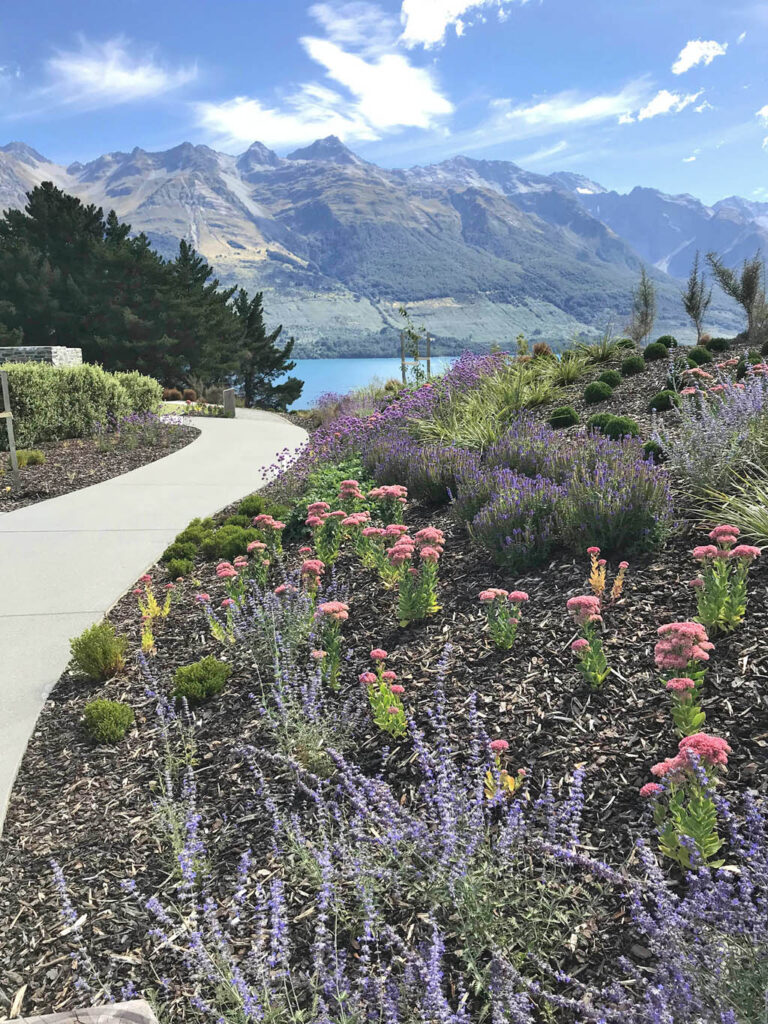 Flowering perennial garden beside a curved path at Blanket Bay Villas, overlooking Lake Wakatipu and the mountains.