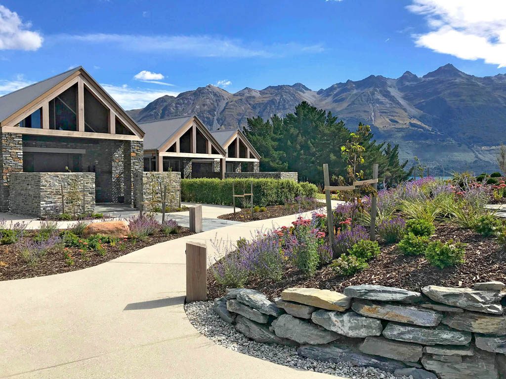 Curved garden path through layered perennial planting and stone walls at Blanket Bay Villas.