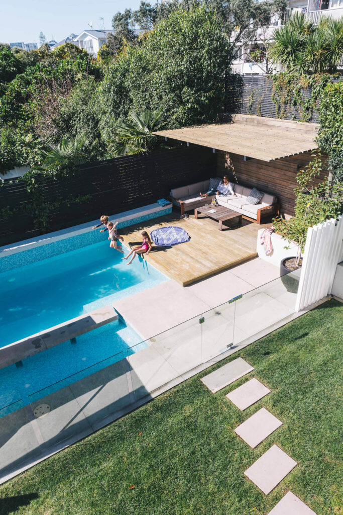 Vertical overview of the compact Freemans Bay pool garden with lawn, paving, timber deck and cabana.