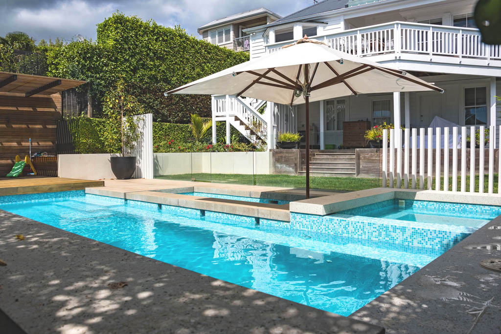 Swimming pool and integrated spa terrace at Freemans Bay with timber decking and white picket fencing.