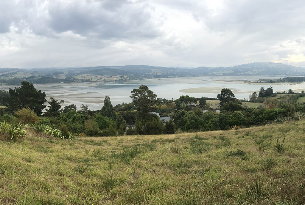 Elevated view across the rural landscape and tidal harbour at Doctors Point, with rolling hills and established vegetation.