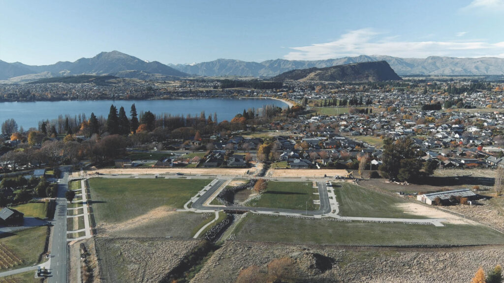 Aerial view of the Studholme Rise development site in Wānaka with Lake Wānaka and the town beyond.